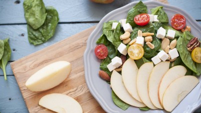 Spinach salad with apple, mixed nuts, and feta