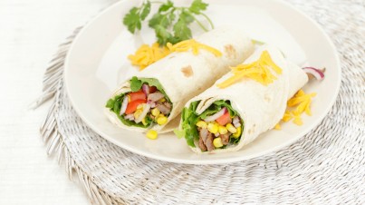 Tortilla wrap with lettuce, beef strips, avocado, tomatoes and Cheddar cheese