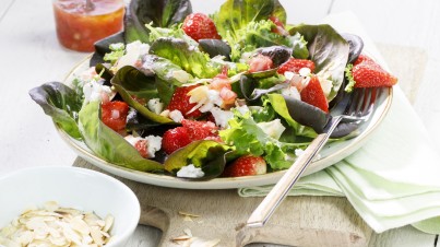 Fresh salad with red butterhead lettuce with strawberries, kale, almonds and goat cheese