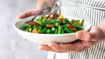 Vegan roerbakschotel met sperzieboontjes en aubergines en zelfgemaakte zoete woksaus met pit