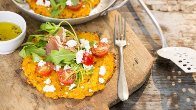 Gezonde pizza van zoete aardappel met rucola, tomaat en prosciutto