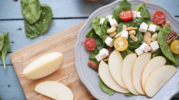 Spinach salad with apple, mixed nuts, and feta