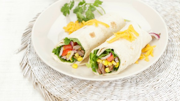 Tortilla wrap with lettuce, beef strips, avocado, tomatoes and Cheddar cheese