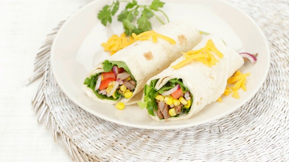 Tortilla-Wrap mit Salat, Rindfleischstreifen, Avocado, Tomaten und Cheddar-Käse Tortilla-Wrap mit Salat, Rindfleischstreifen, Avocado, Tomaten und Cheddar-Käse