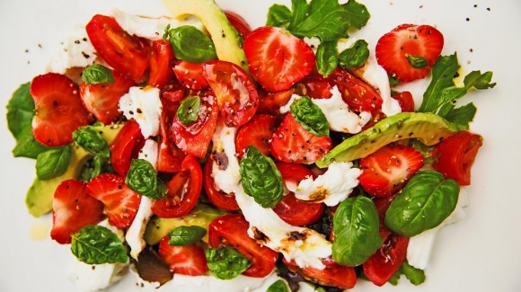 Breakfast salad with strawberries, avocado, tomato, mozzarella and pomegranate syrup